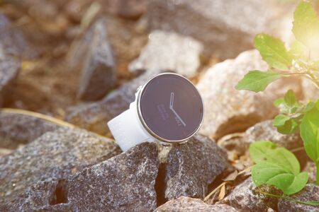 Sport watch for triathlon on the granite gravel. Smart watch for tracking daily activity and strength training. Sun beam lights.の写真素材