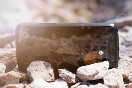 Broken glass of smartphone on granite stones. Selective focus.の写真素材