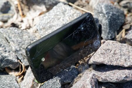 Broken cellphone abandoned and lost among the gravel.の写真素材