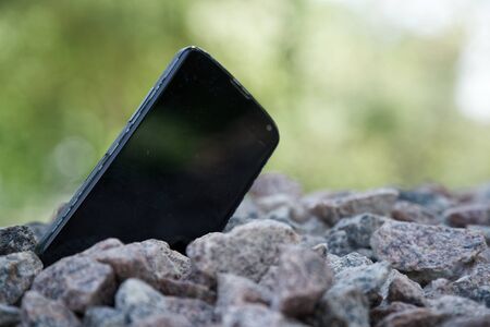 Broken cellphone abandoned and lost among the gravel.の写真素材