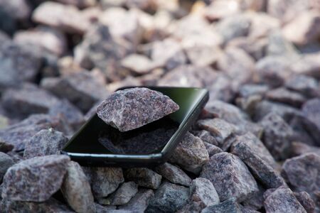 Cell phone with broken glass on gravel granite stones, unbreakable gadget.の写真素材