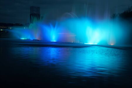 Colorful water fountains with laser and light reflection over lake.の写真素材