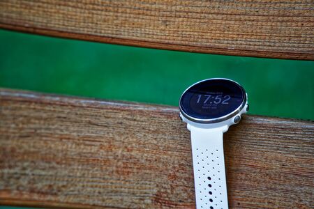 Sport watch for running white color on wooden bench. Fitness watch for tracking daily activity and power trainingの写真素材