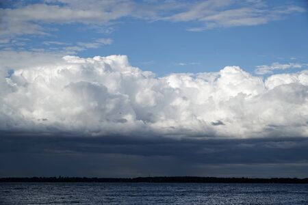 Storm cloud and lighthouse. Dramatic cloudscape texture. Dark heavy thunderstorm clouds before rain. Overcast rainy bad weather. Storm warning. Natural blue background of cumulonimbus.の写真素材