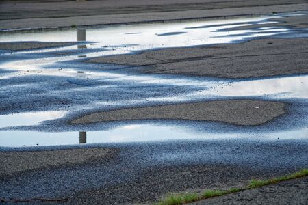 Sky reflected in a puddle of water on pavement, Early morning sunriseの写真素材