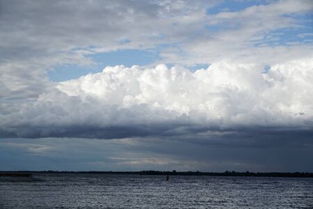 Storm cloud and lighthouse. Dramatic cloudscape texture. Dark heavy thunderstorm clouds before rain. Overcast rainy bad weather. Storm warning. Natural blue background of cumulonimbus.の写真素材