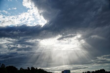 Rays of bright sun peep out from behind dark clouds, sun break after storm.の写真素材
