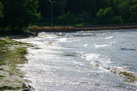 Surging wave on the Kyiv sea reservoir, water reflection, foam and sun beam.の写真素材
