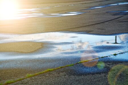Sky reflected in a puddle of water on pavement, Early morning sunriseの写真素材
