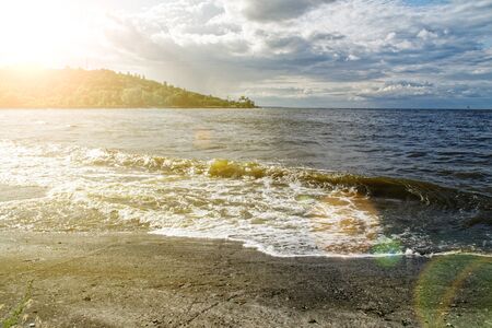 Surging wave on the Kyiv sea reservoir, water reflection, foam and sun beam.の写真素材