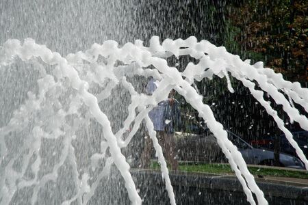 Fountain in the sun backlight. The fountains gushing sparkling water from pipe in park.の写真素材