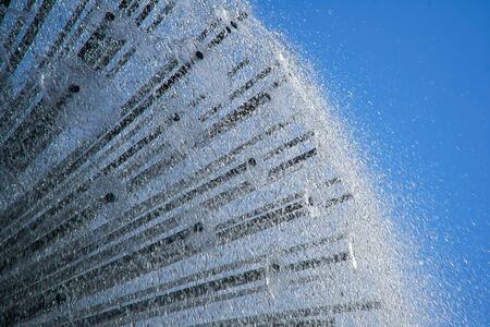 Fountain in the sun backlight against blue sky. The fountains gushing sparkling water from pipe in park.の写真素材