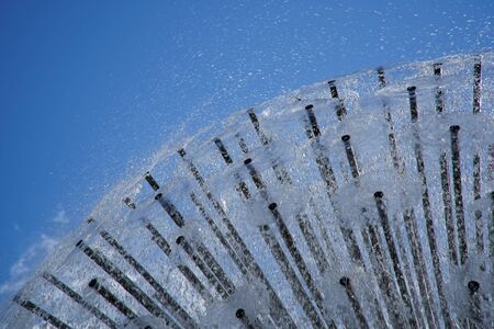 Fountain in the sun backlight against blue sky. The fountains gushing sparkling water from pipe in park.の写真素材