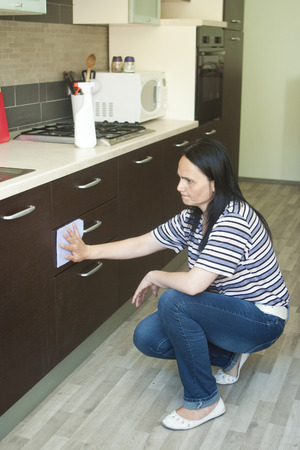 Adult woman kneeling to clean the lower furnitureの写真素材