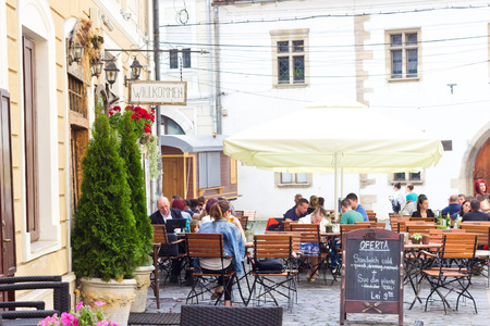 CLUJ-NAPOCA, ROMANIA - MAY 20, 2014: People resting under umbrella at street restaurant in quite central part of Cluj.のeditorial素材