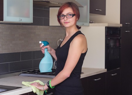 Attractive female teenager cleaning furniture at the kitchenの写真素材