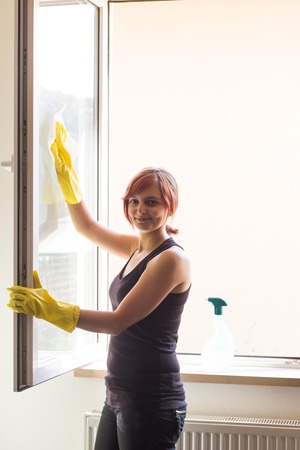 Cute young girl cleaning window at the kitchenの写真素材