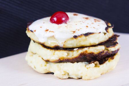 Cottage cheese pancakes decorated with sour cream and cherryの写真素材