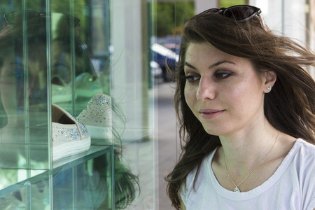 Excited female customer watching shop window displays outdoorsの写真素材