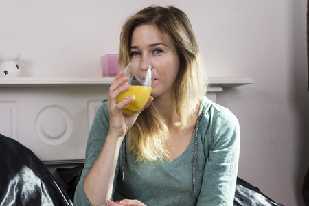 Portrait of young woman having breakfast in bedの写真素材