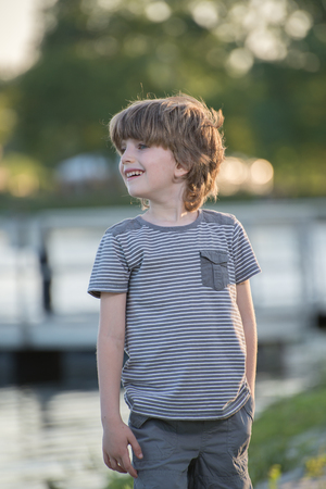 Portrait of a little boy,one hand in his pocket in park with blurred backgroundの写真素材