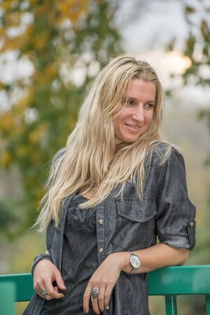 Attractive blonde young woman in a park with blurred backgroundの写真素材