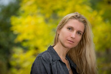 Attractive blonde young woman in a park with blurred backgroundの写真素材