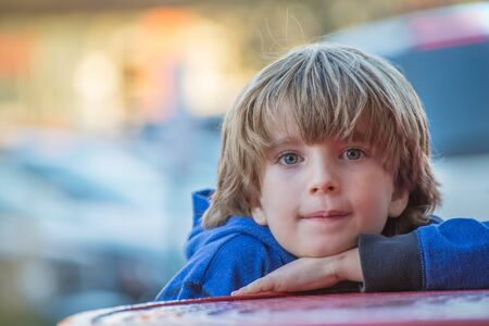 Portrait of a young blonde boy in the city with blurred backgroundの写真素材