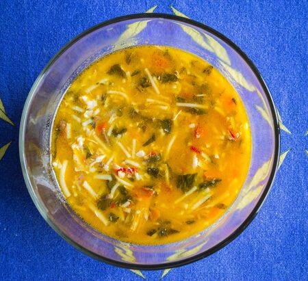 CHICKEN NOODLE SOUP IN A BOWL ON A BLUE TABLECLOTHの写真素材