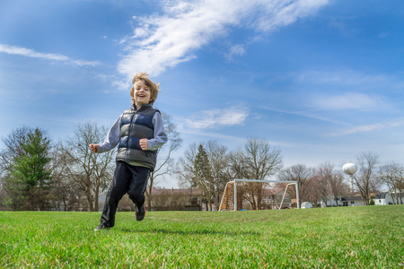 A little boy running on a soccer fieldの写真素材