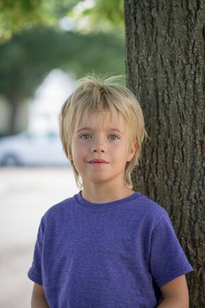 Portrait of a young boy in front of a treeの写真素材