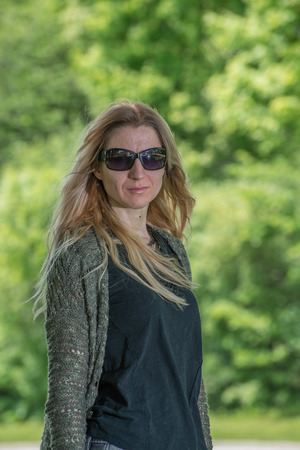 Attractive blonde young woman in a park with blurred backgroundの写真素材