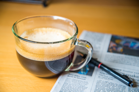 Cup of coffee, newspaper and a penの写真素材