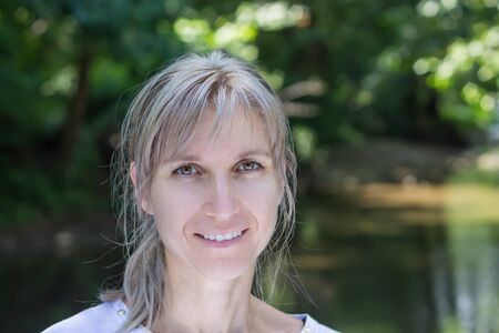 Attractive blonde young woman in a park with blurred backgroundの写真素材