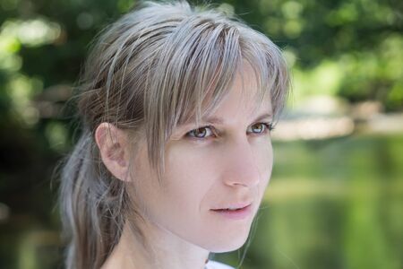 Attractive blonde young woman in a park with blurred backgroundの写真素材