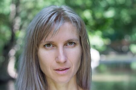 Attractive blonde young woman in a park with blurred backgroundの写真素材