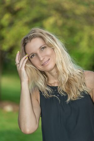 Attractive blonde young woman in a park with blurred backgroundの写真素材