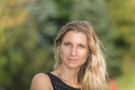 Attractive blonde young woman in a park with blurred backgroundの写真素材