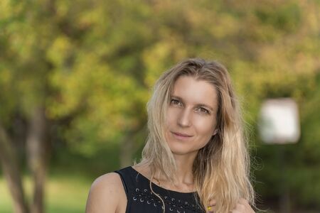 Attractive blonde young woman in a park with blurred backgroundの写真素材
