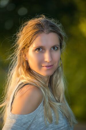 Attractive blonde young woman in a park with blurred backgroundの写真素材