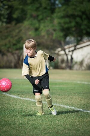 Portrait of a boy playing soccer, ready to kick the ballの写真素材