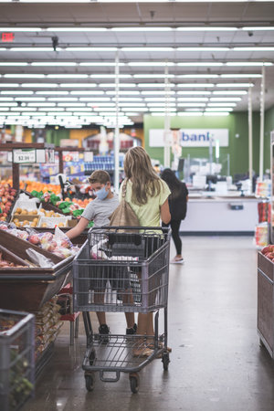 Chicago,IL- August 21, 2021:Mother and  child wearing masks shopping at supermarket for editorial...