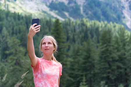 Woman taking selfie with mobile phone in the mountains. Summer vacation conceptの写真素材
