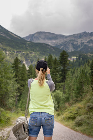 Young woman standing on a mountain road and looking at the landscape.の写真素材