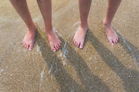 Two pairs of kids feet on the sand in the water .Family on vacations. Feet and the grains of sand.の写真素材