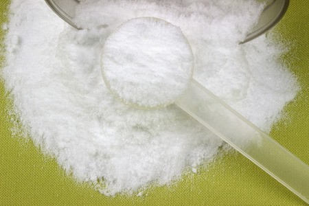 Creatine monohydrate powder and measure spoon on a green cover.の写真素材