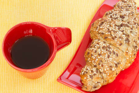 Breakfast coffee and whole wheat croissant on a tablecloth.の写真素材