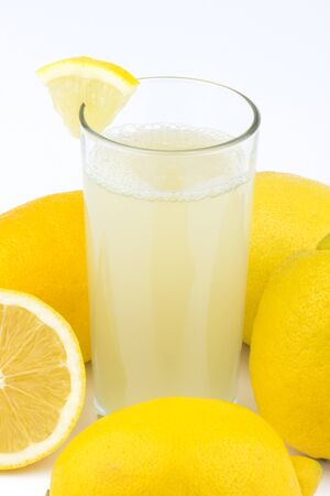 Glass of water with lemon slices and lemons on white background.の写真素材