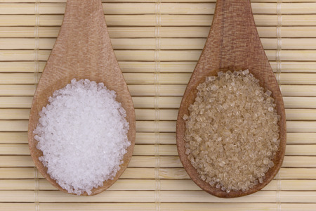 Wooden spoon with two types sugar on bamboo placemat.の写真素材