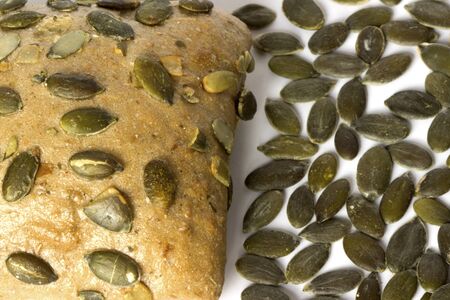 One small bread with pumpkin seeds close up on white background.の写真素材